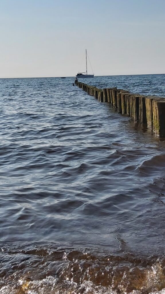 Holzbuhnen am Meer mit Boot in der Ferne – Beispiel für die Drittelregel in der Landschaftsfotografie