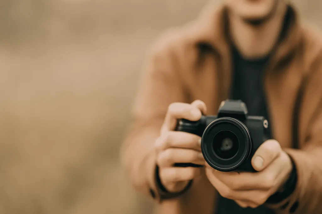 Ein Anfänger hält draußen eine Kamera in der Hand – Symbolbild für kreative Fotoideen und Fotografie-Challenges für Einsteiger