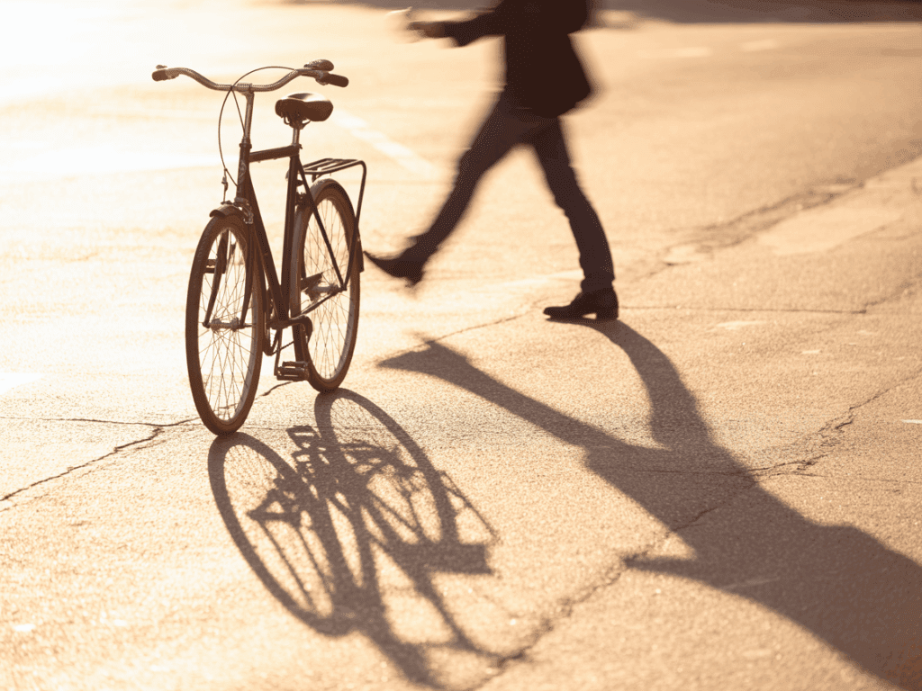 Lange Schatten eines Fahrrads und einer Person auf Asphalt bei Sonnenuntergang – effektvolle Fotoidee für Anfänger im Gegenlicht
