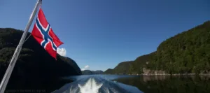 Bootsfahrt mit norwegischer Flagge und weitem Blick in die Berge – idealer Einstieg in die Landschaftsfotografie und Symbol für fotografisches Abenteuer